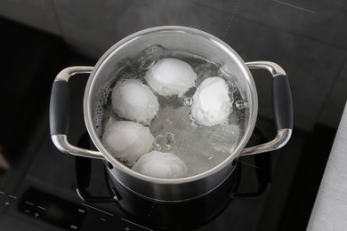 Photo of Chicken eggs boiling in pot on electric stove, above view
