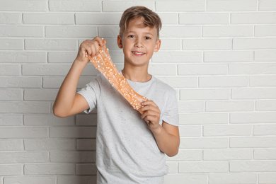 Photo of Preteen boy with slime near white brick wall