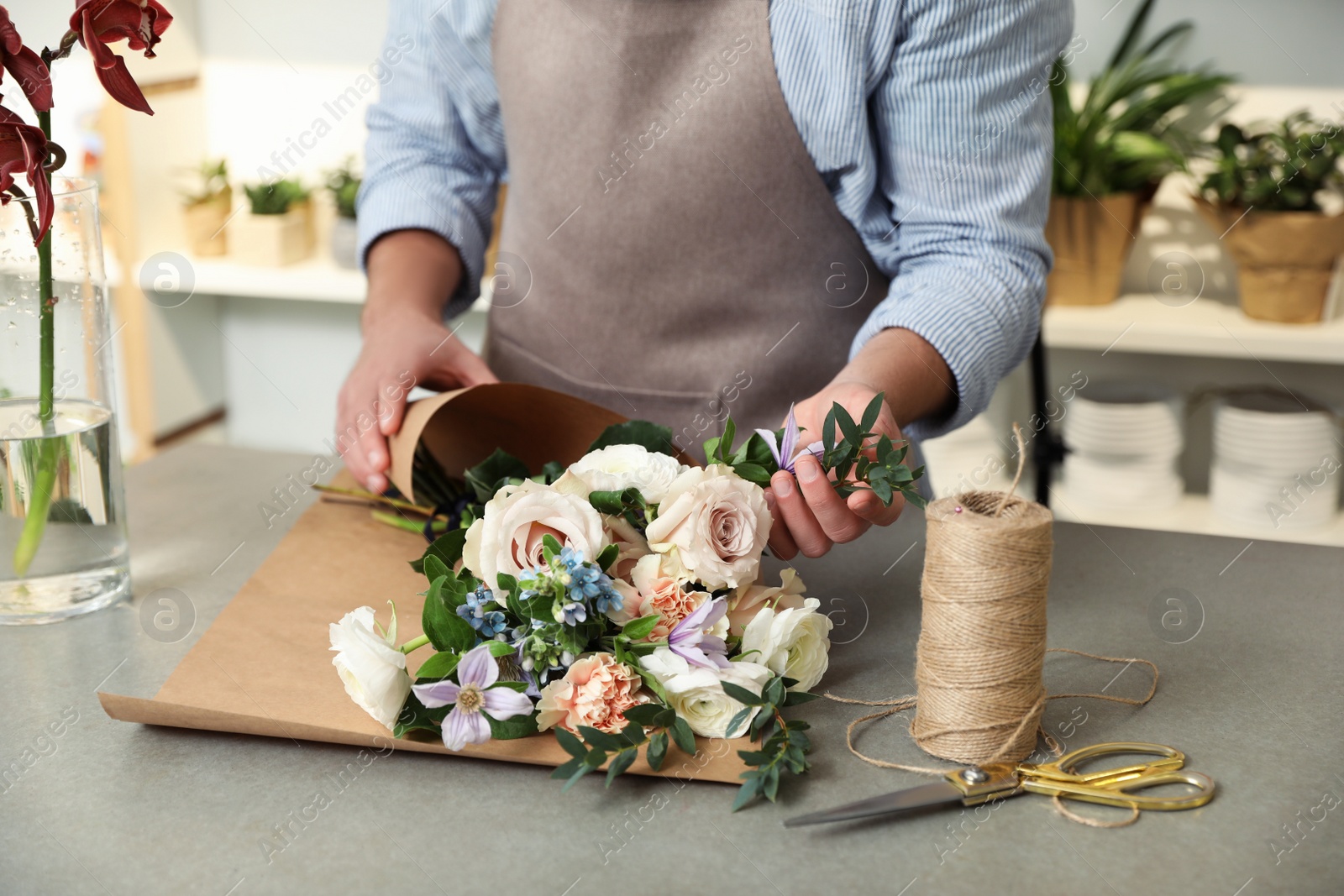 Photo of Florist making bouquet with fresh flowers at table, closeup