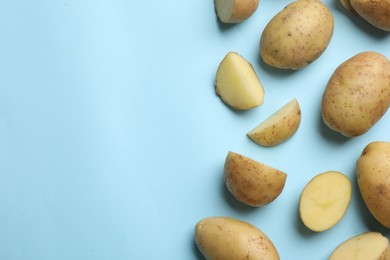 Photo of Fresh raw potatoes on light blue background, flat lay. Space for text