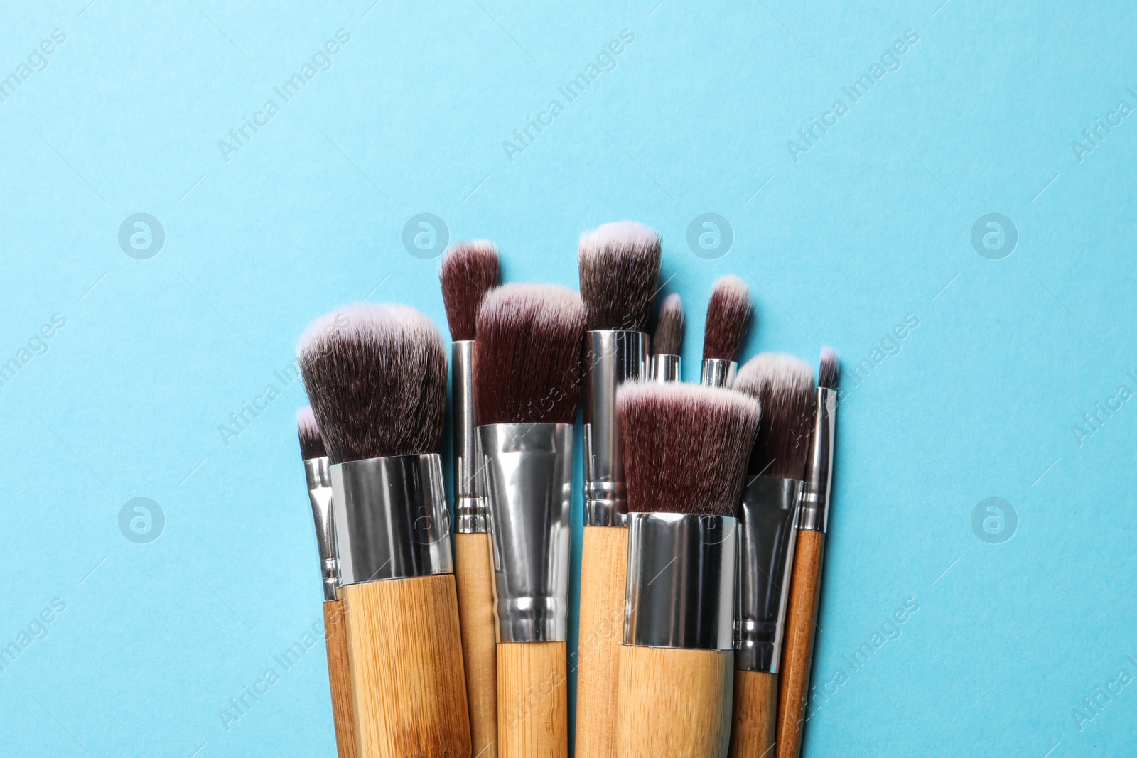 Photo of Different makeup brushes on light blue background, flat lay. Space for text