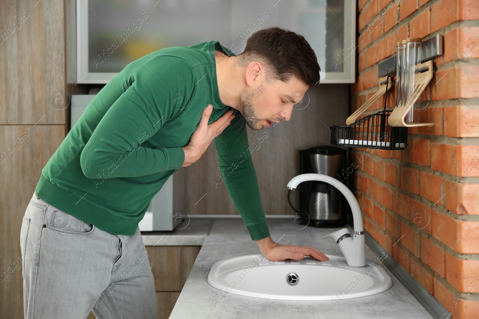 Photo of Young man having nausea in kitchen. Feeling sick