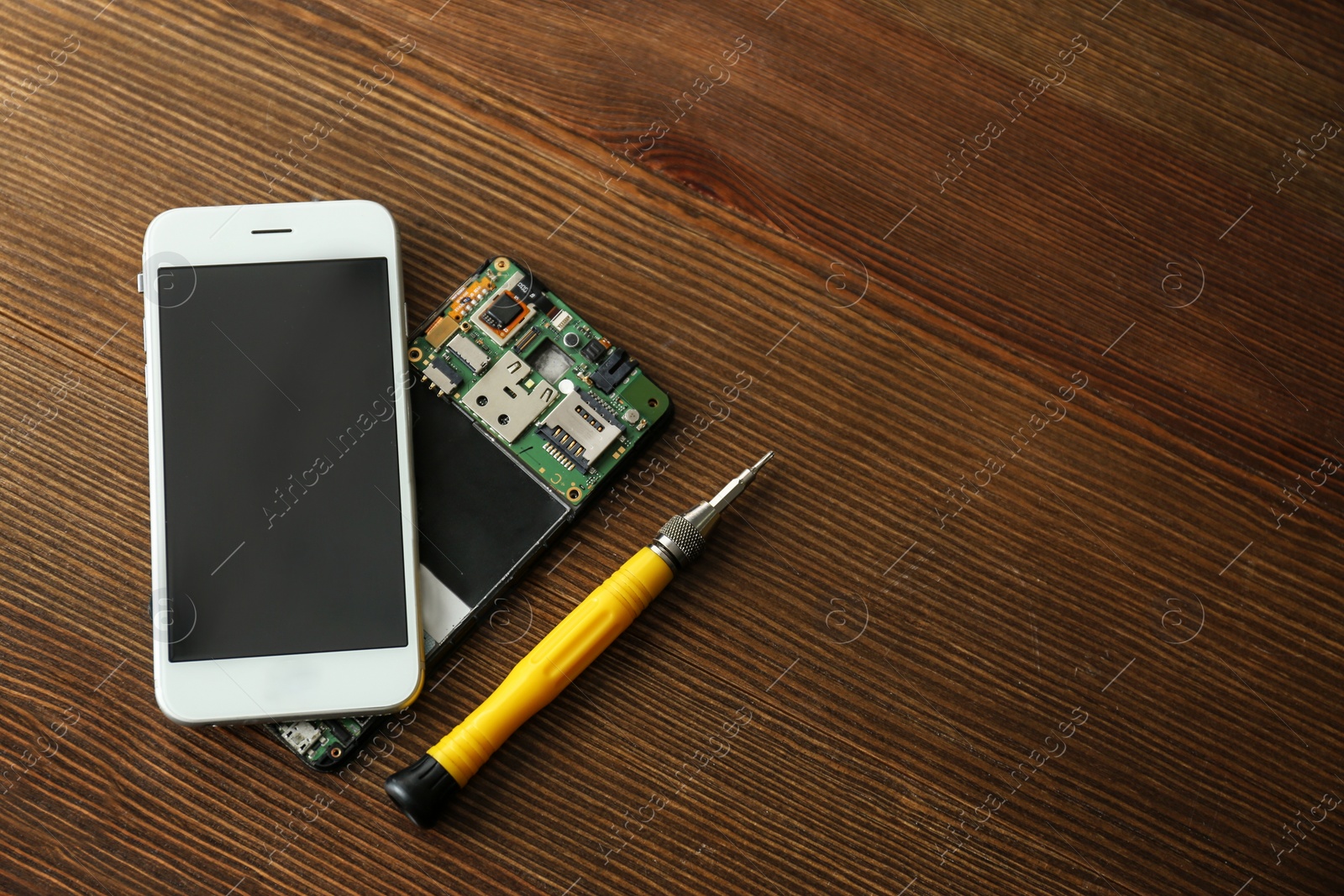 Photo of Flat lay composition of mobile phones and screwdriver on wooden table, space for text. Repairing service