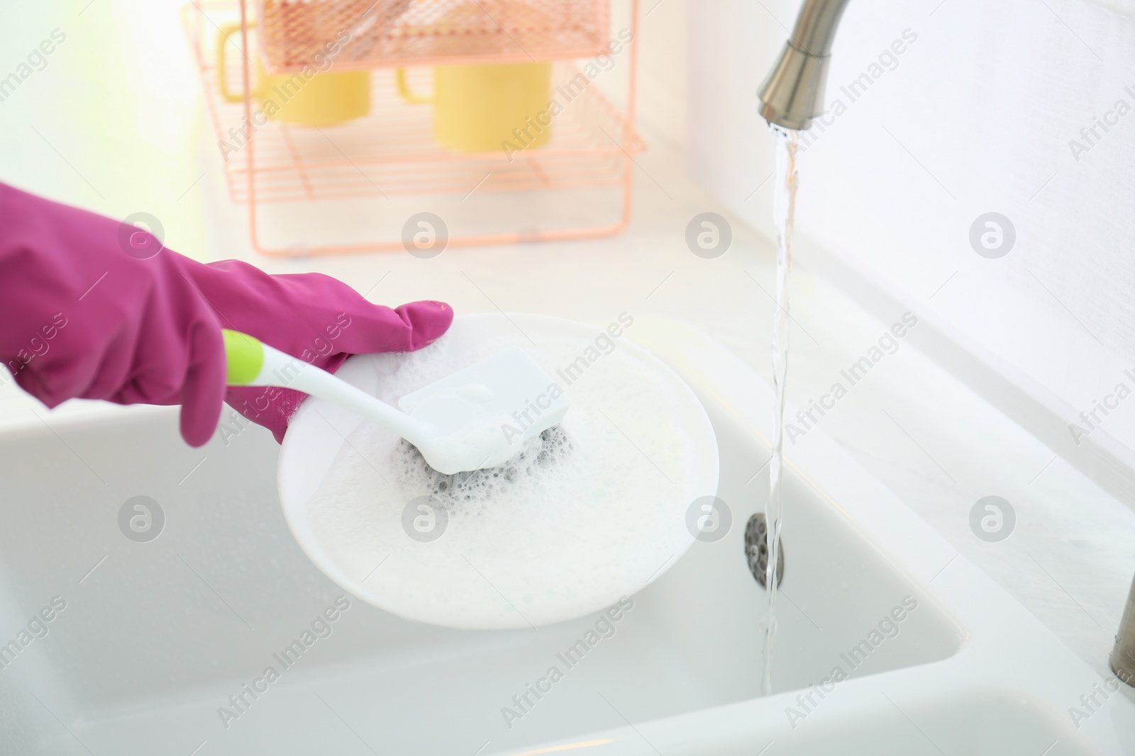 Photo of Woman washing ceramic plate in kitchen, closeup