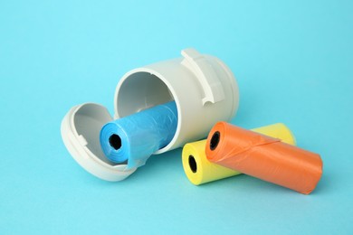 Photo of Dog waste bags and dispenser on light blue background