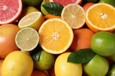 Photo of Different fresh citrus fruits and leaves as background, above view