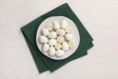 Many peeled hard boiled quail eggs on white wooden table, top view