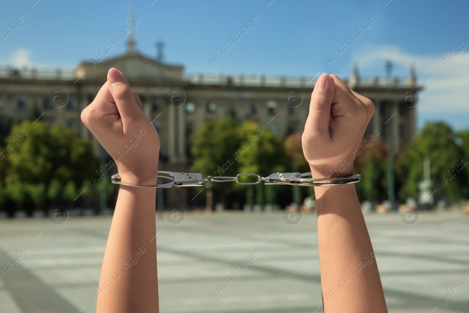 Photo of Woman in handcuffs on city street, closeup