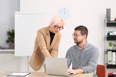Photo of Boss and employee with laptop discussing work issues in office