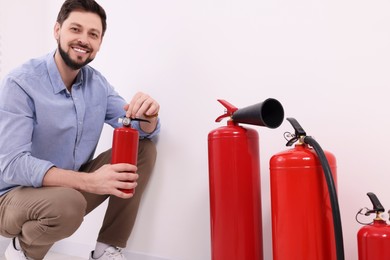 Photo of Man checking quality of fire extinguishers indoors