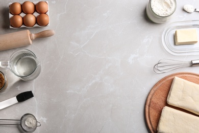 Photo of Frame made with puff pastry dough and ingredients on grey table, flat lay. Space for text