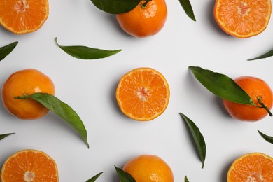 Photo of Delicious tangerines and green leaves on white background, flat lay