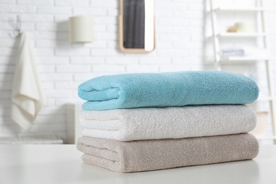 Photo of Stack of fresh towels on table in bathroom, closeup