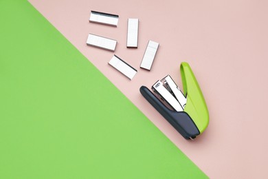 Photo of New bright stapler with staples on color background, fat lay. Space for text