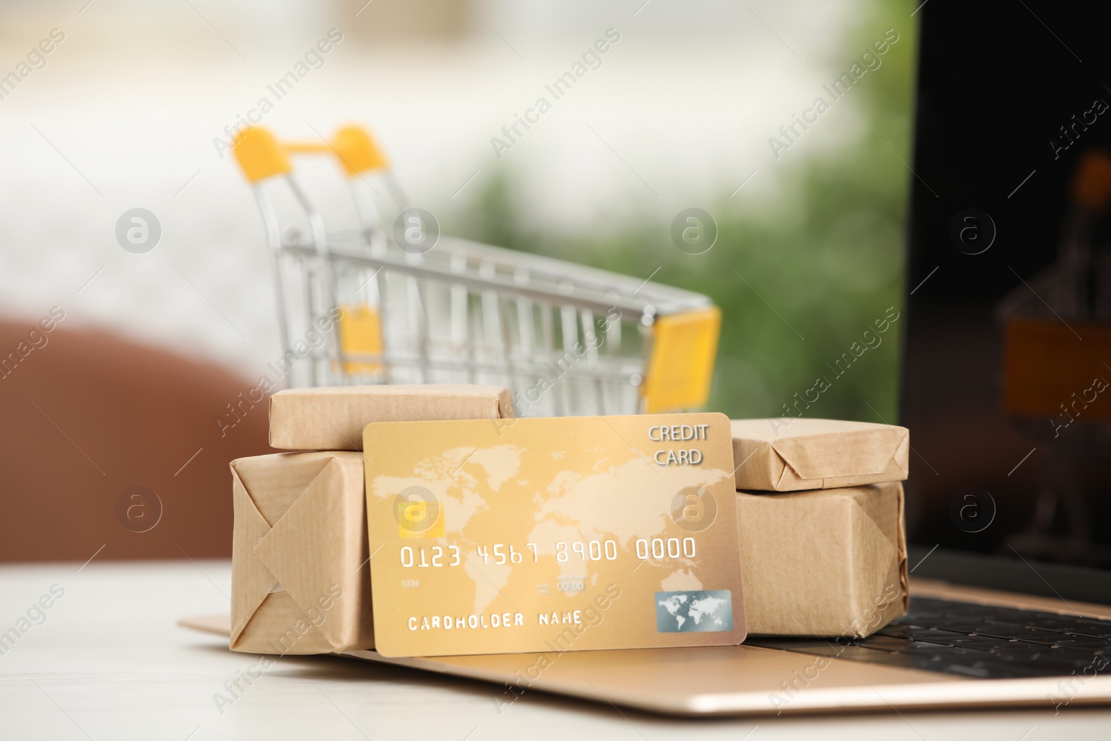 Photo of Online payment concept. Bank card and small boxes with laptop on white table