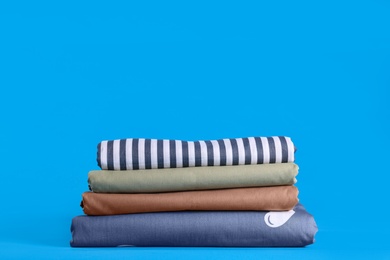 Stack of clean bed sheets on blue background