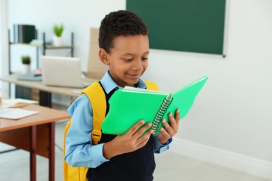 Photo of African-American boy wearing school uniform with backpack in classroom