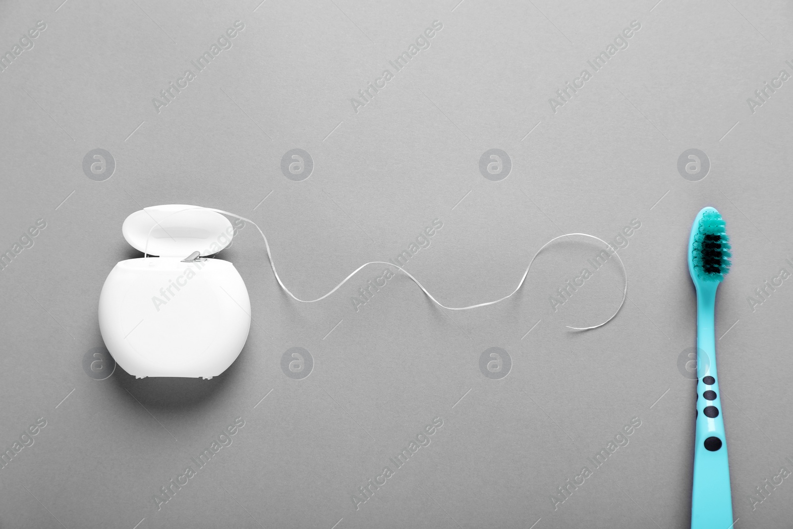 Photo of Container with dental floss and toothbrush on light grey background, flat lay