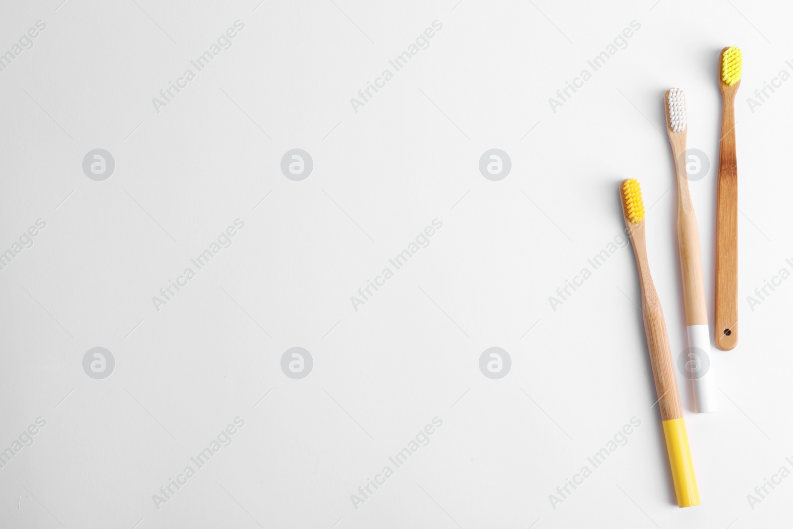 Photo of Bamboo toothbrushes on white background, top view. Space for text