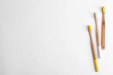 Photo of Bamboo toothbrushes on white background, top view. Space for text