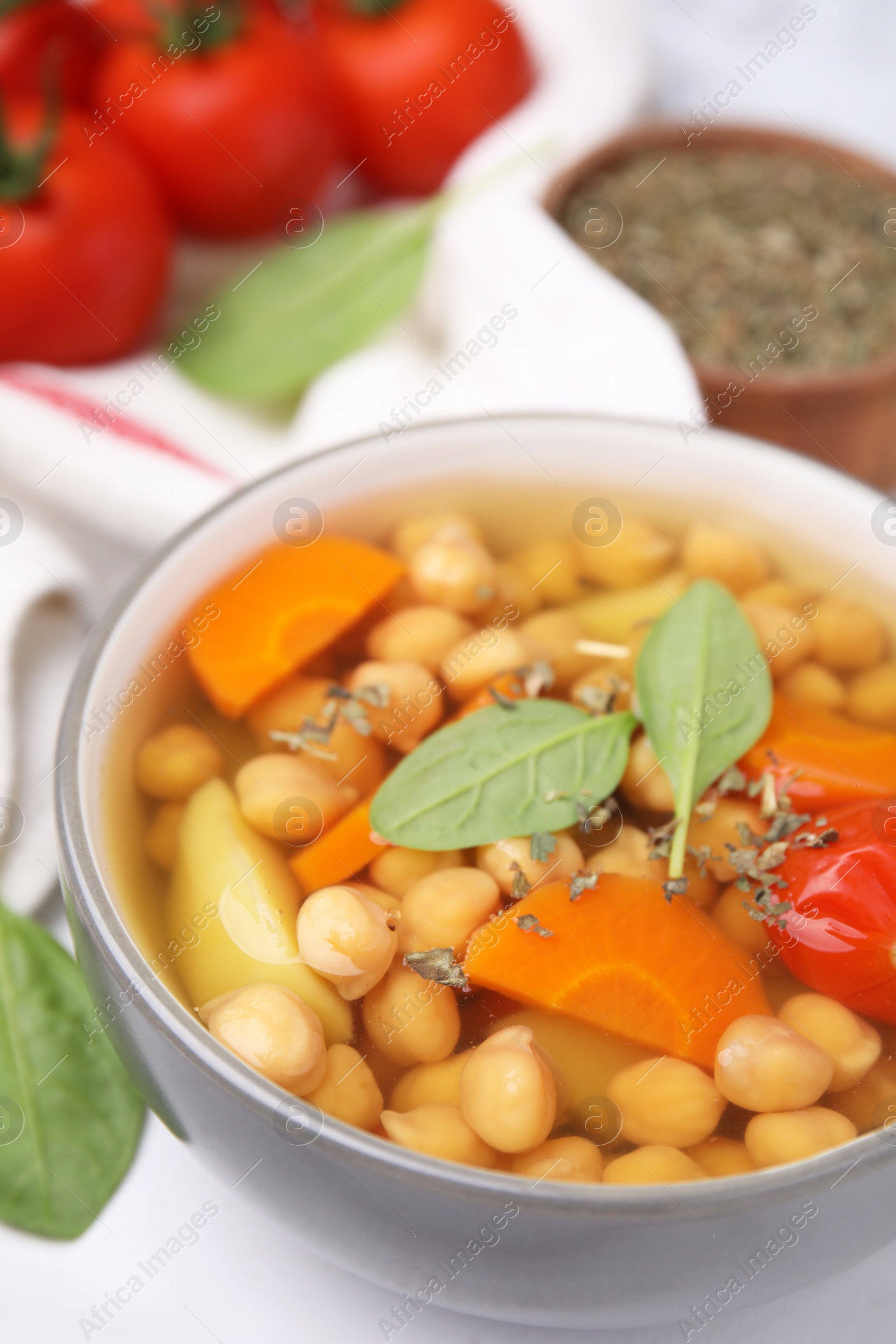 Photo of Tasty chickpea soup in bowl and spices on white table