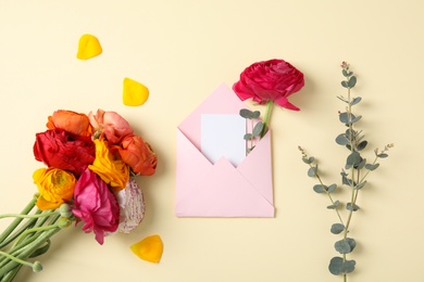 Photo of Flat lay composition with beautiful ranunculus flowers and card in envelope on color background. Space for text