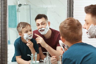 Photo of Dad and son with shaving foam at mirror
