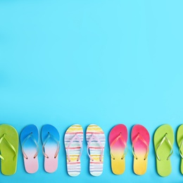 Different flip flops and space for text on blue background, flat lay. Summer beach accessories