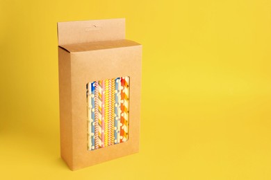 Photo of Box with many paper drinking straws on orange background. Space for text