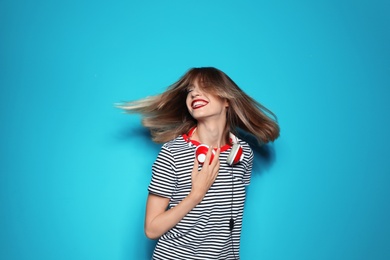 Beautiful young woman with healthy long blonde hair and headphones on color background