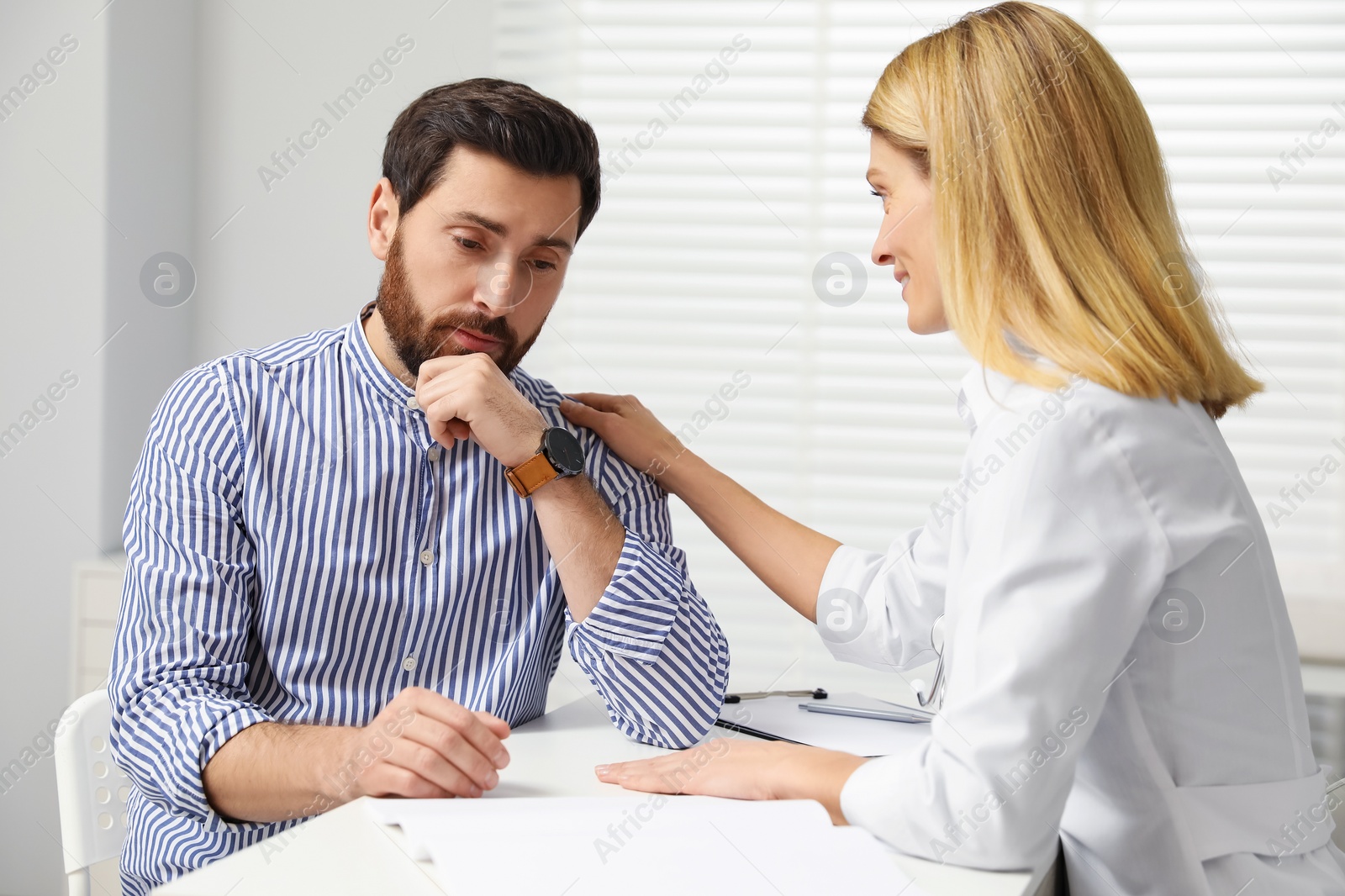 Photo of Doctor consulting patient at white table in clinic