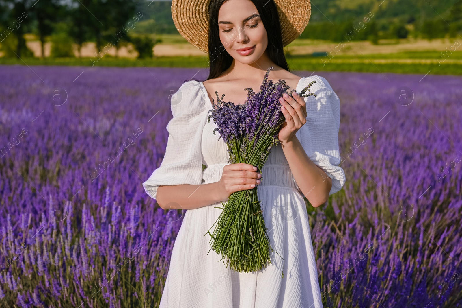 Photo of Beautiful young woman with bouquet in lavender field