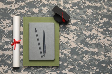 Photo of Stationery, diploma and mortarboard on camouflage background, flat lay with space for text. Military education