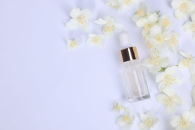 Essential oil in bottle and beautiful jasmine flowers on white background, flat lay. Space for text