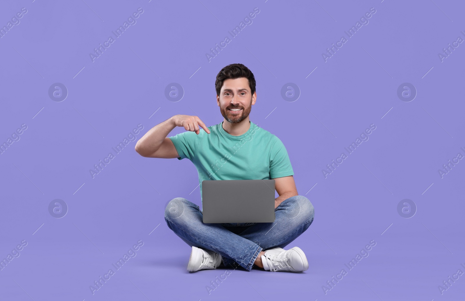Photo of Happy man with laptop on purple background