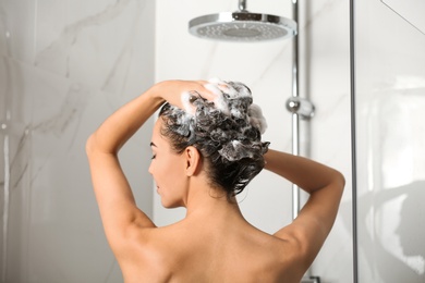 Image of Beautiful young woman washing hair in shower at home