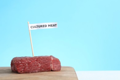 Photo of Sample of lab grown beef labeled Cultured Meat on wooden table. Space for text