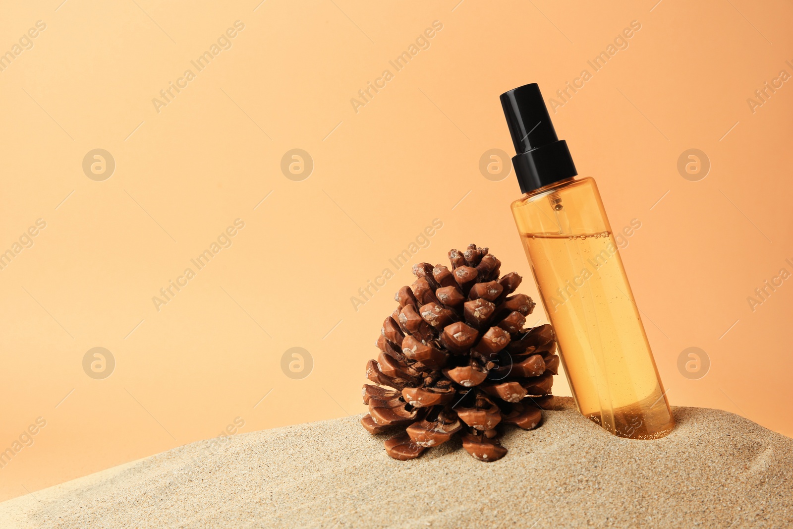 Photo of Bottle with serum and cone on sand against orange background, space for text. Cosmetic product