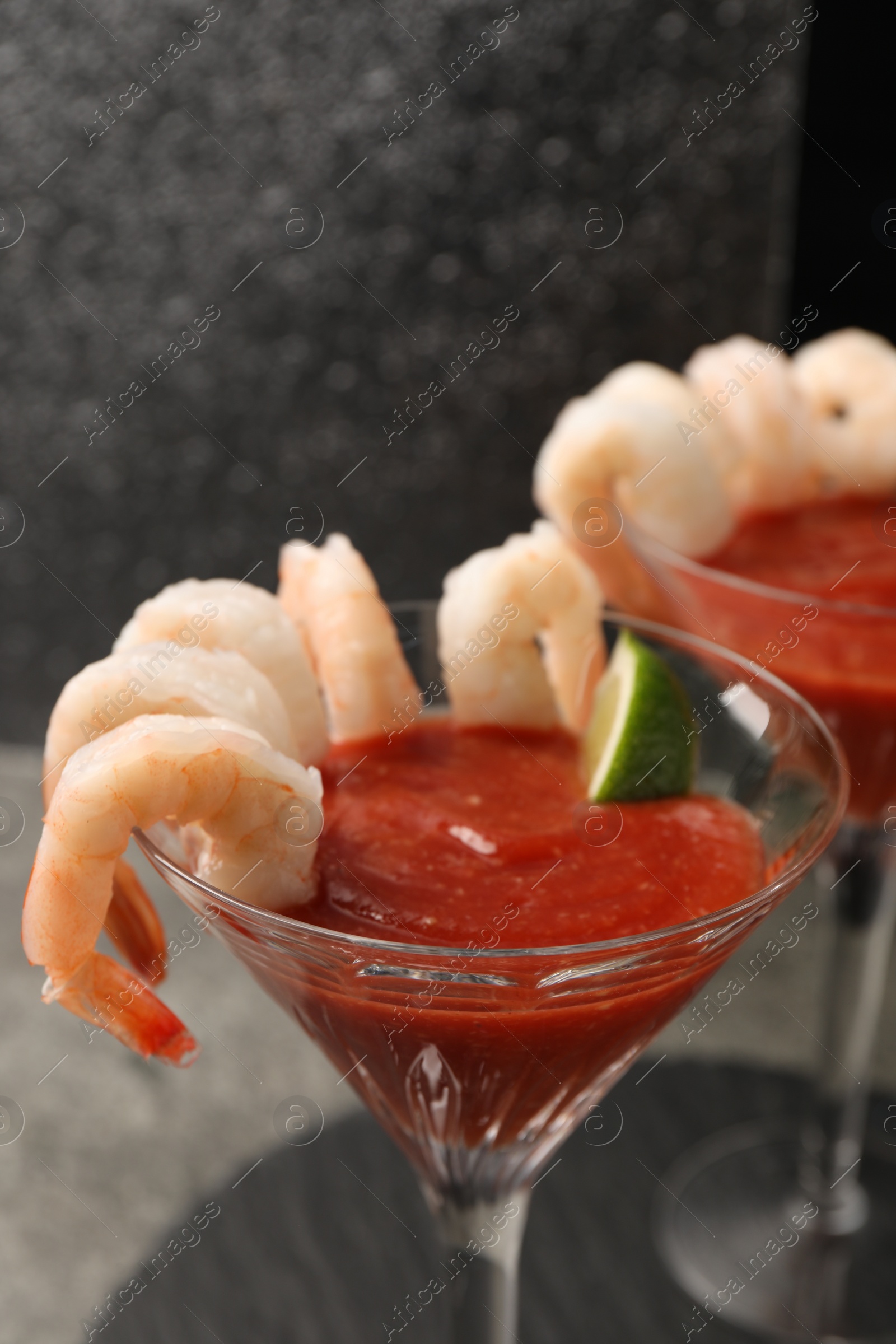 Photo of Tasty shrimp cocktail with sauce and lime in glasses on table, closeup