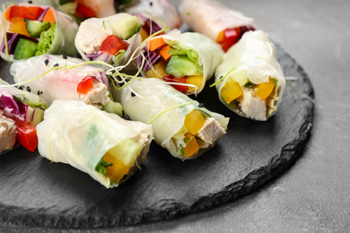 Photo of Delicious rolls wrapped in rice paper on grey table, closeup