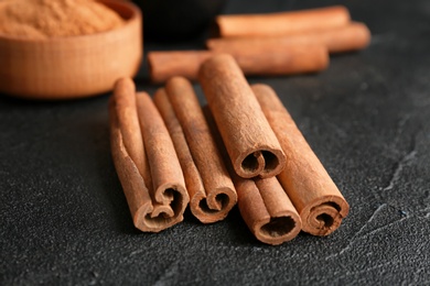 Photo of Aromatic cinnamon sticks on dark grey background, closeup