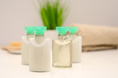 Photo of Mini bottles of cosmetic products on white table against blurred background. Space for text