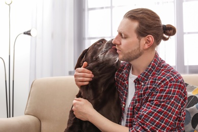 Photo of Adorable brown labrador retriever with owner on couch indoors