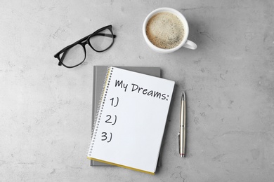 Image of Notebook with dreams list on grey table, flat lay 