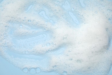 White washing foam on light blue background, top view