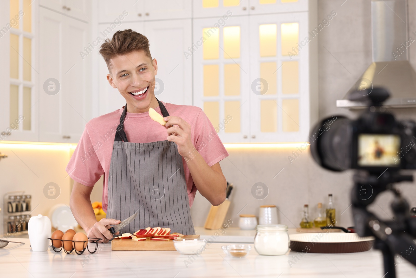 Photo of Smiling food blogger cooking while recording video in kitchen