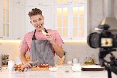 Smiling food blogger cooking while recording video in kitchen