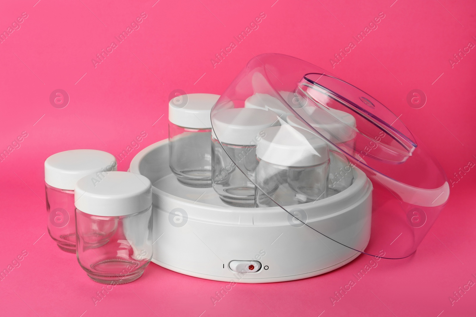 Photo of Modern yogurt maker with empty jars on pink background