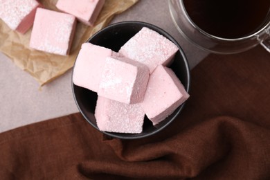 Bowl of delicious sweet marshmallows with powdered sugar on light brown table, flat lay