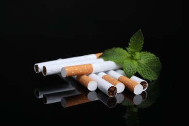 Photo of Menthol cigarettes and mint on black background